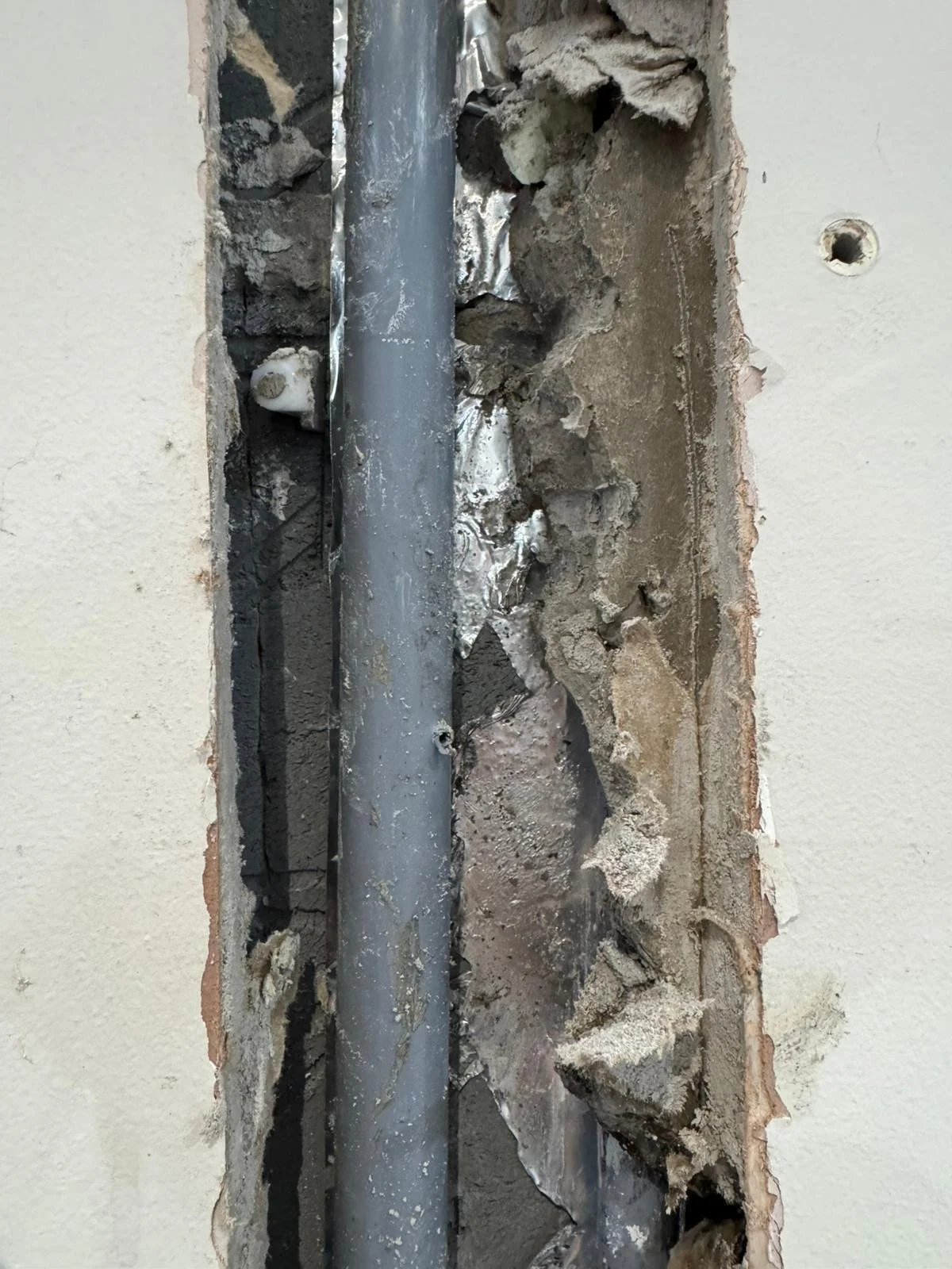 Concealed pipe exposed in a chased wall opening during an emergency plumbing repair in Chester