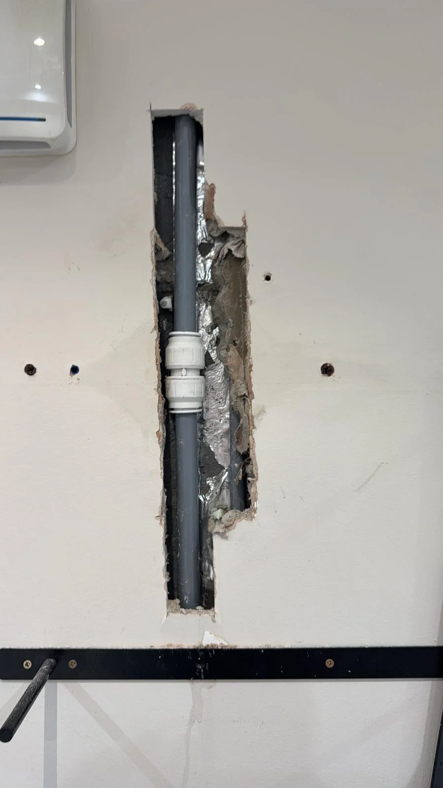 Repaired pipe in a wall chase with a new section jointed using push-fit couplings, before the wall was made good