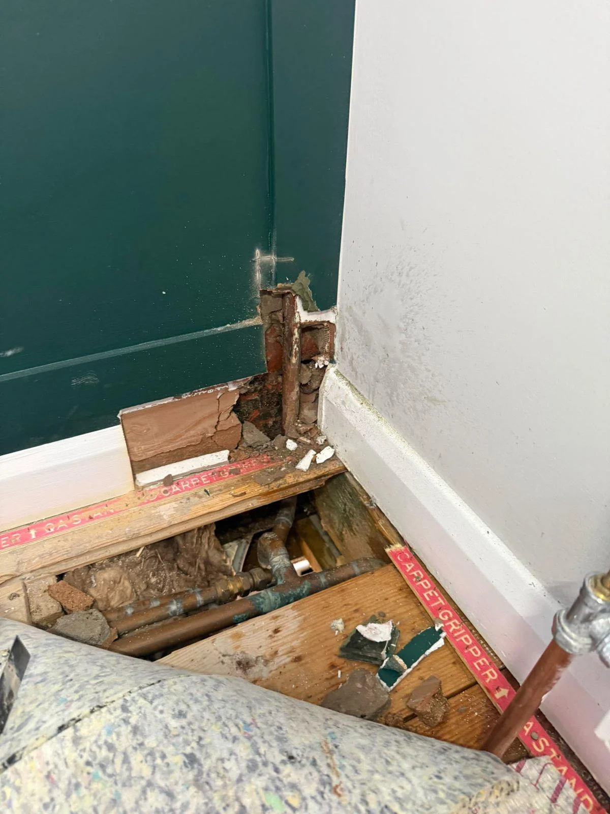 First-floor wall opened at skirting level and floorboards lifted to expose concealed copper pipework