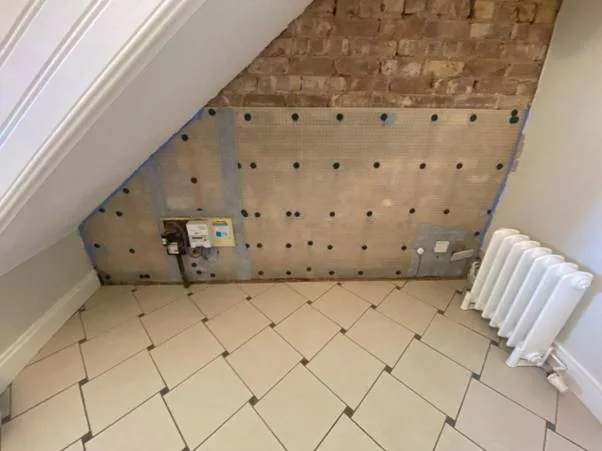 Studded damp proof membrane fitted to a wall behind a radiator