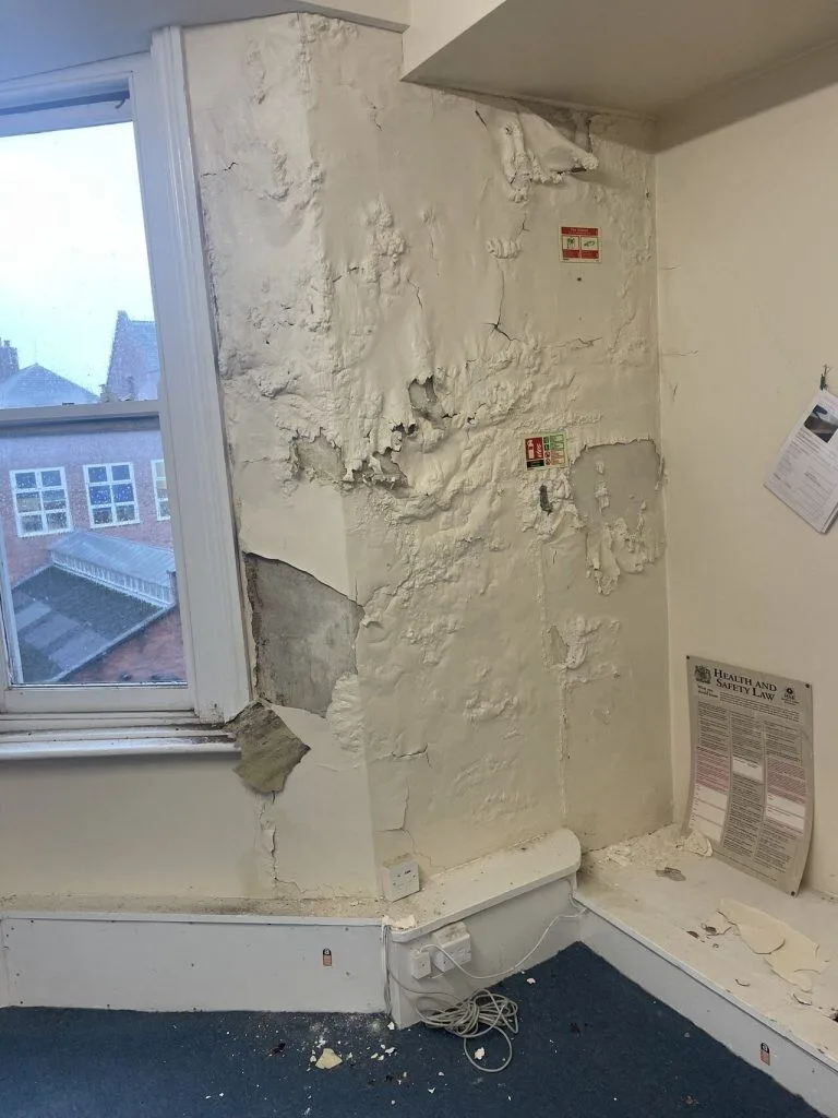Plaster damaged by penetrating damp on an internal wall beside a window