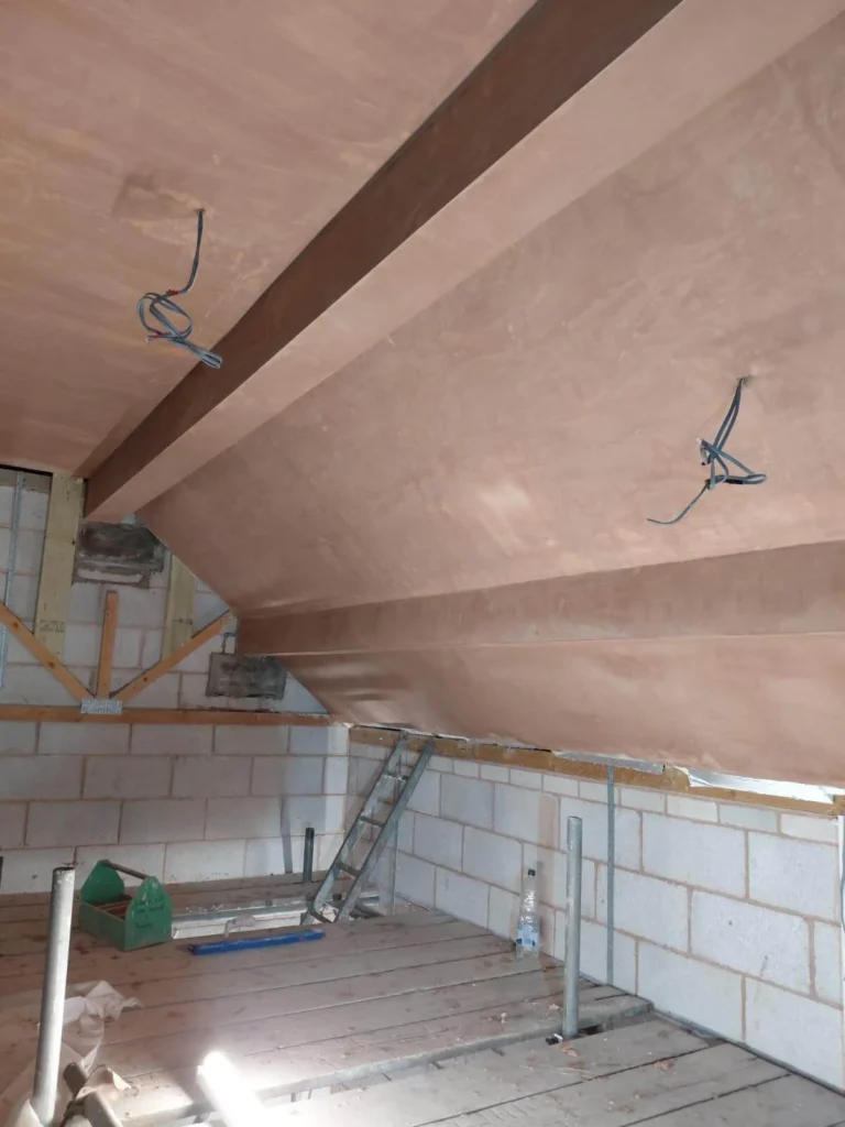 Loft space with fully plastered ceiling and exposed steel beam encasement.