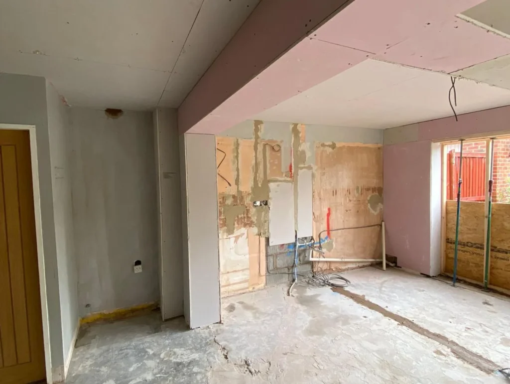 Interior renovation phase showing plastered openings after structural steel beam installation.