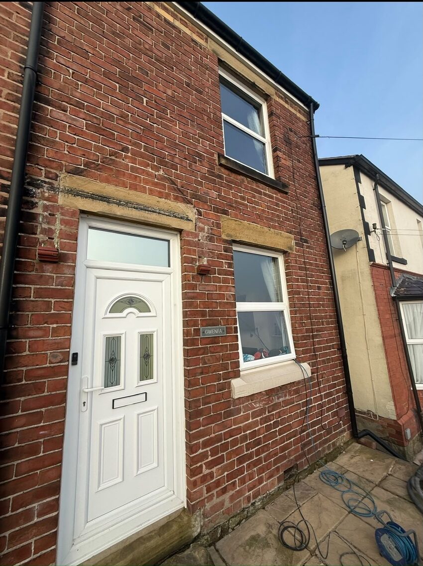 Front elevation of a Bebington property before repointing, showing worn mortar joints and earlier cement patch repairs above the door