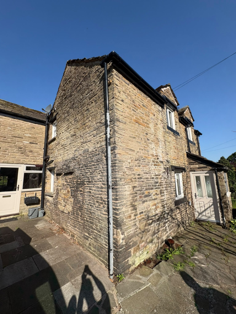 Stone gable of a cottage in Thurstaston, Wirral before repointing, with eroded and open mortar joints
