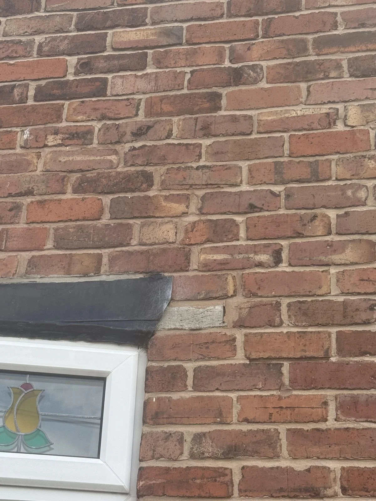 Failed concrete boot lintel over a window opening on a terraced house in Deeside, Flintshire, with step cracking running up through the brickwork above it