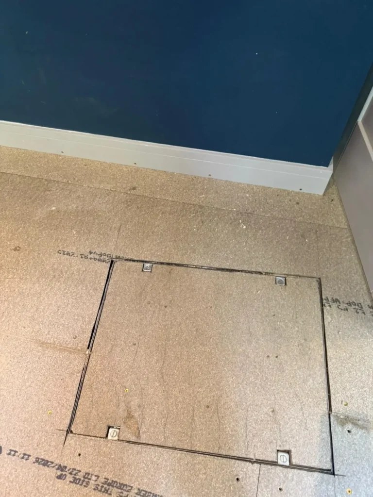 New chipboard floor deck with a sealed recessed-tray manhole cover fitted flush over the inspection chamber