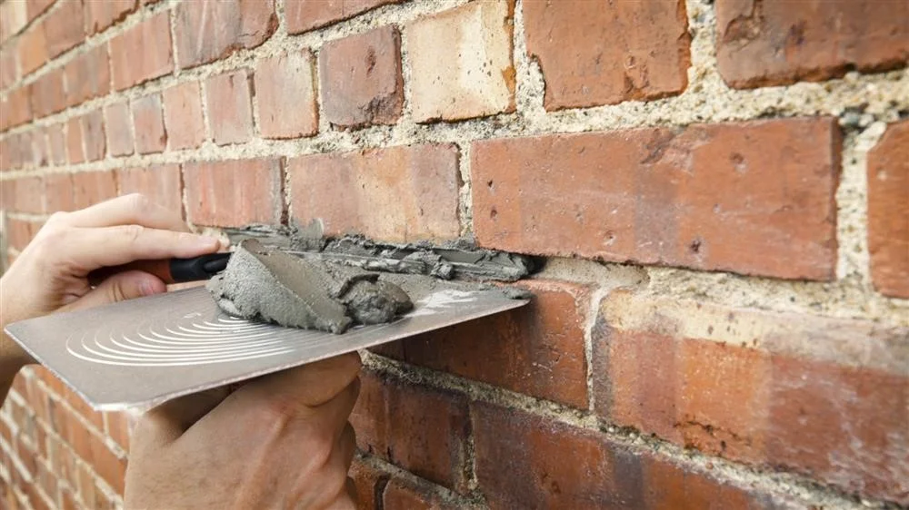 Mortar being worked into a raked-out joint with a pointing trowel