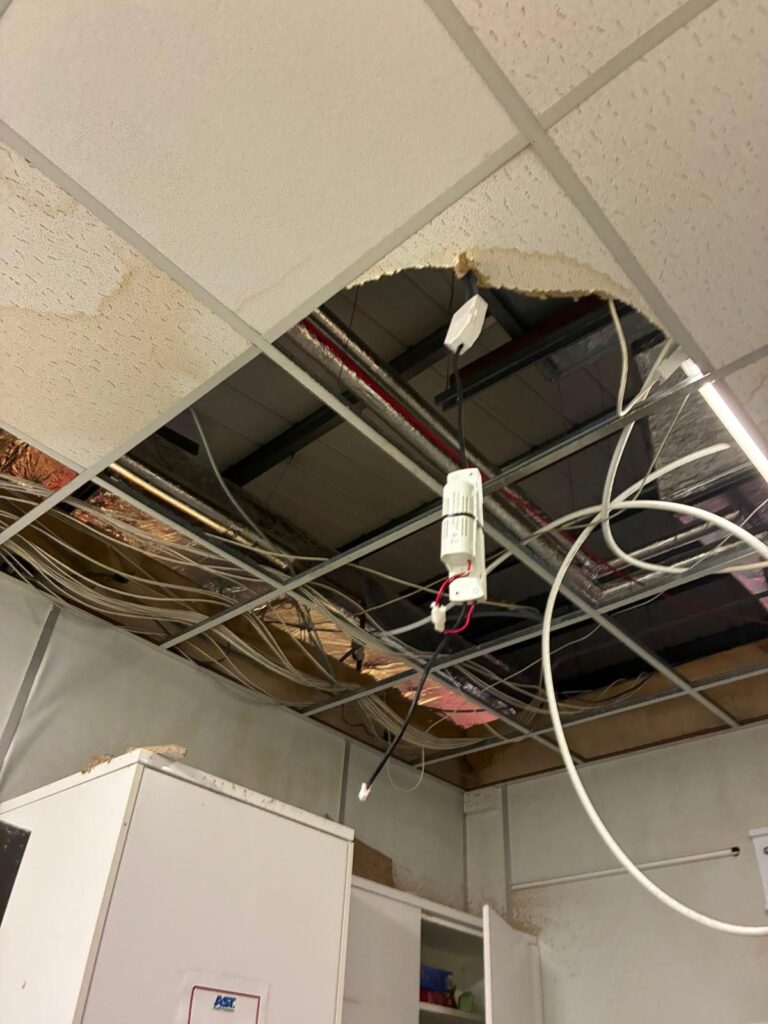 Ceiling opened up after water damage, exposing cabling and conduit for inspection before reinstatement