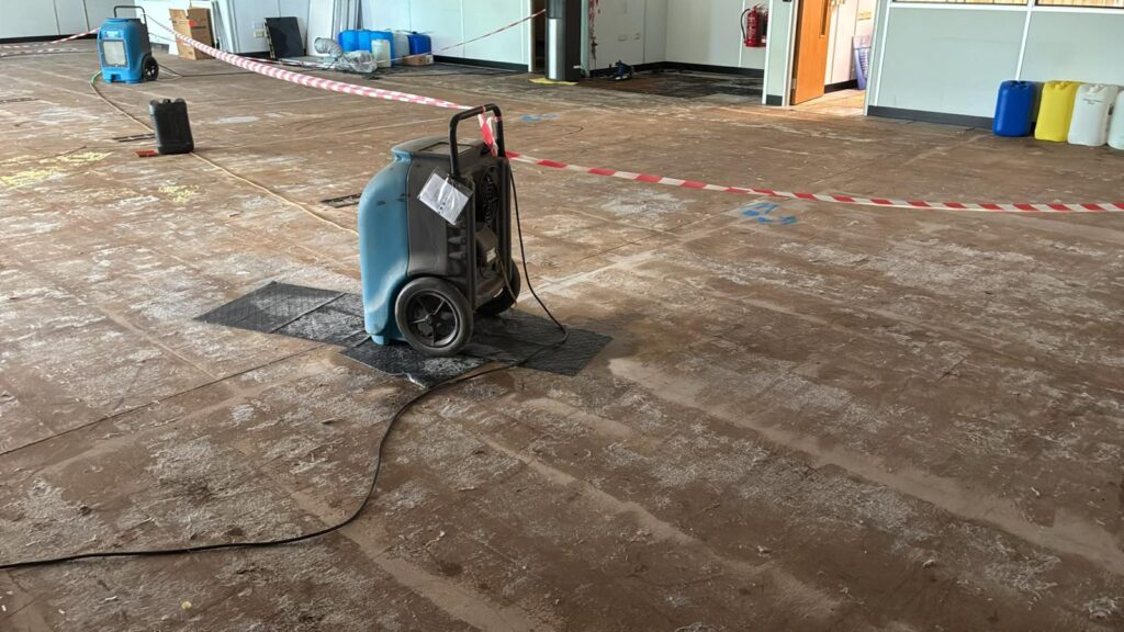 Stripped-out commercial floor with drying hoses in place after flood water removal