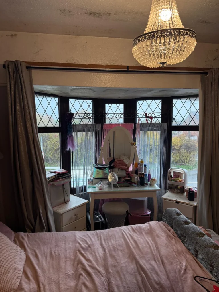 Condensation mould staining on the ceiling above a bay window in a bedroom