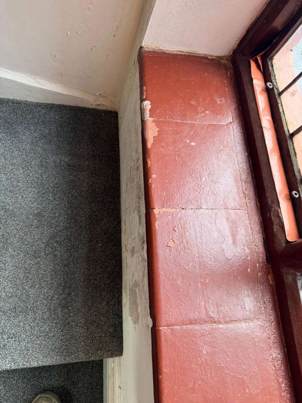 Insulated board fitted against a coated wall beside a window reveal