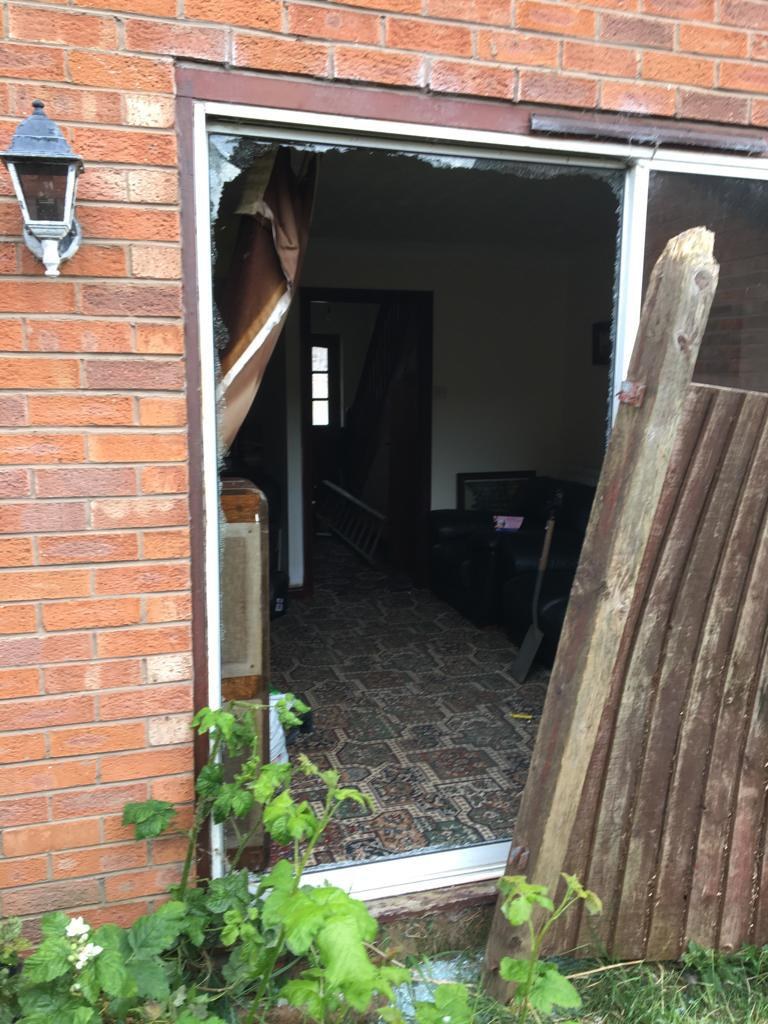 Sliding patio door of a house in Chester with the glass smashed after a break-in, the living room visible through the empty frame