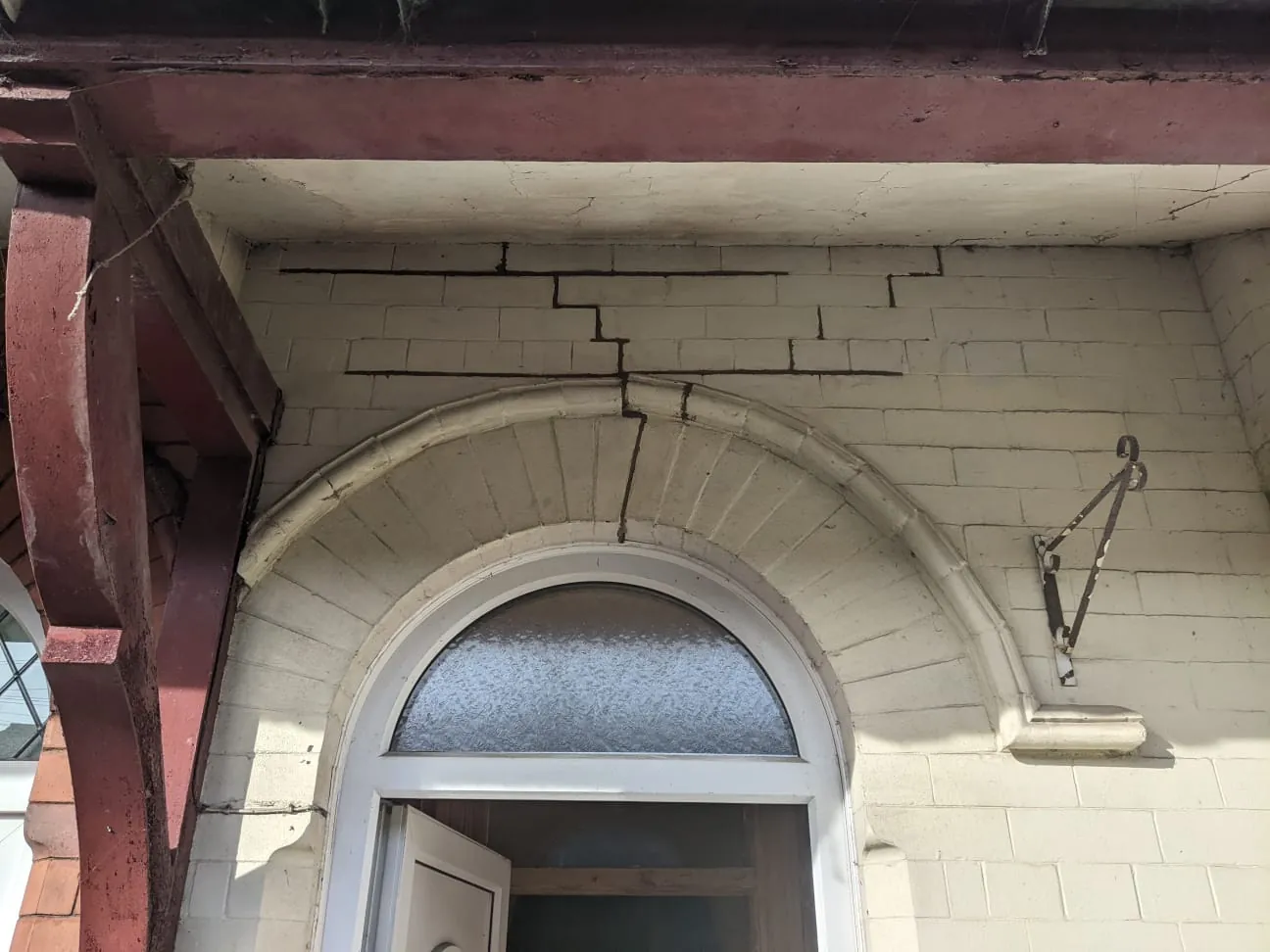 Cracking through a painted brick arch over a front door, stepping up through the brickwork above it