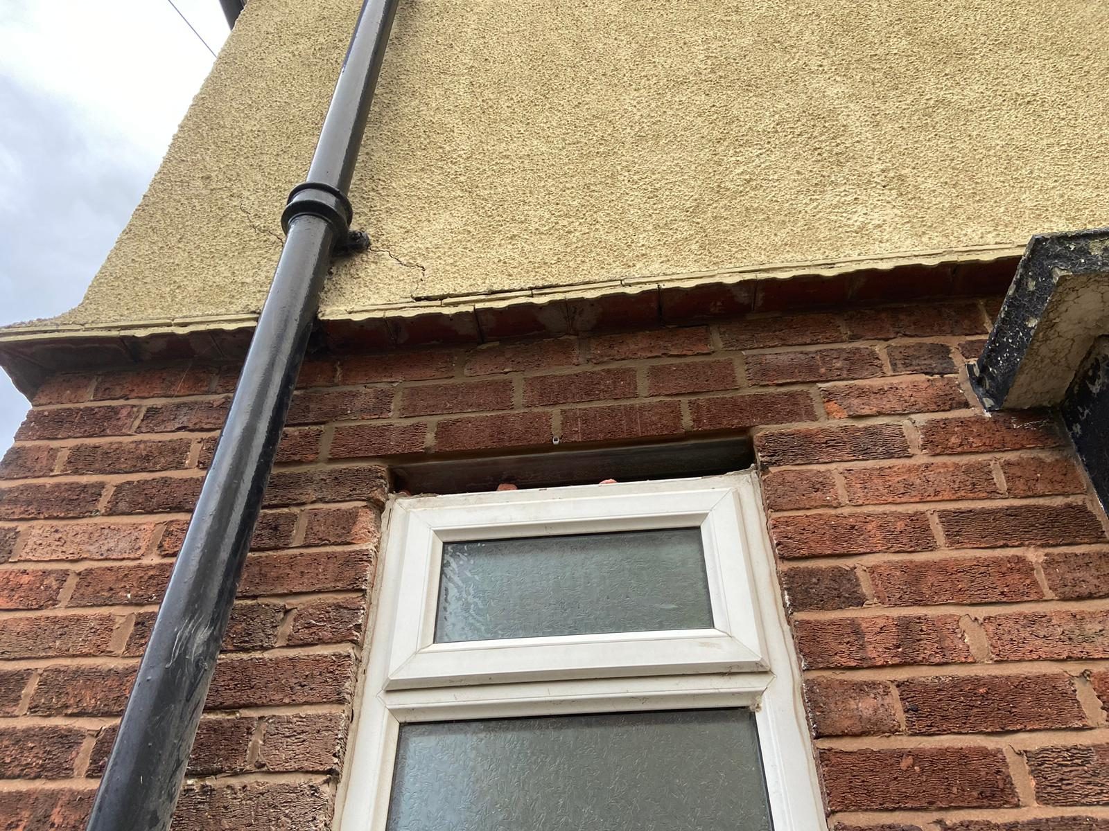 Void above a window head where the lintel has failed, with cracking to the render above