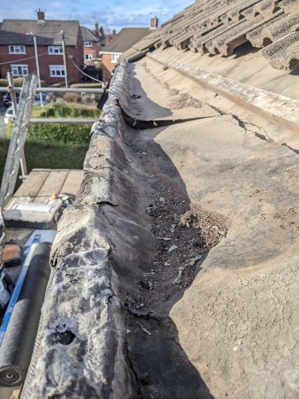 The old underlay at the eaves, perished and split along its length with grit and debris collected in the low point