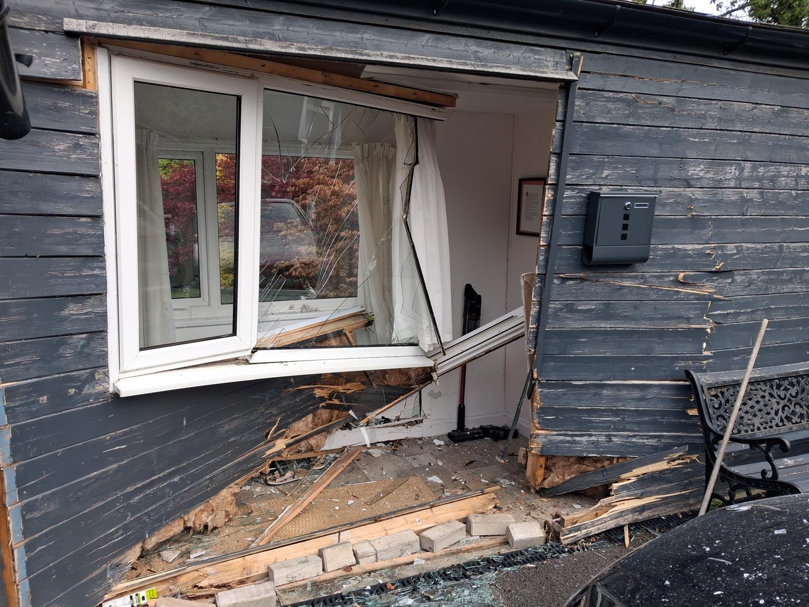 Timber-clad wall of a bungalow porch in Wirral with the cladding, studwork and window pushed in after a car drove into it