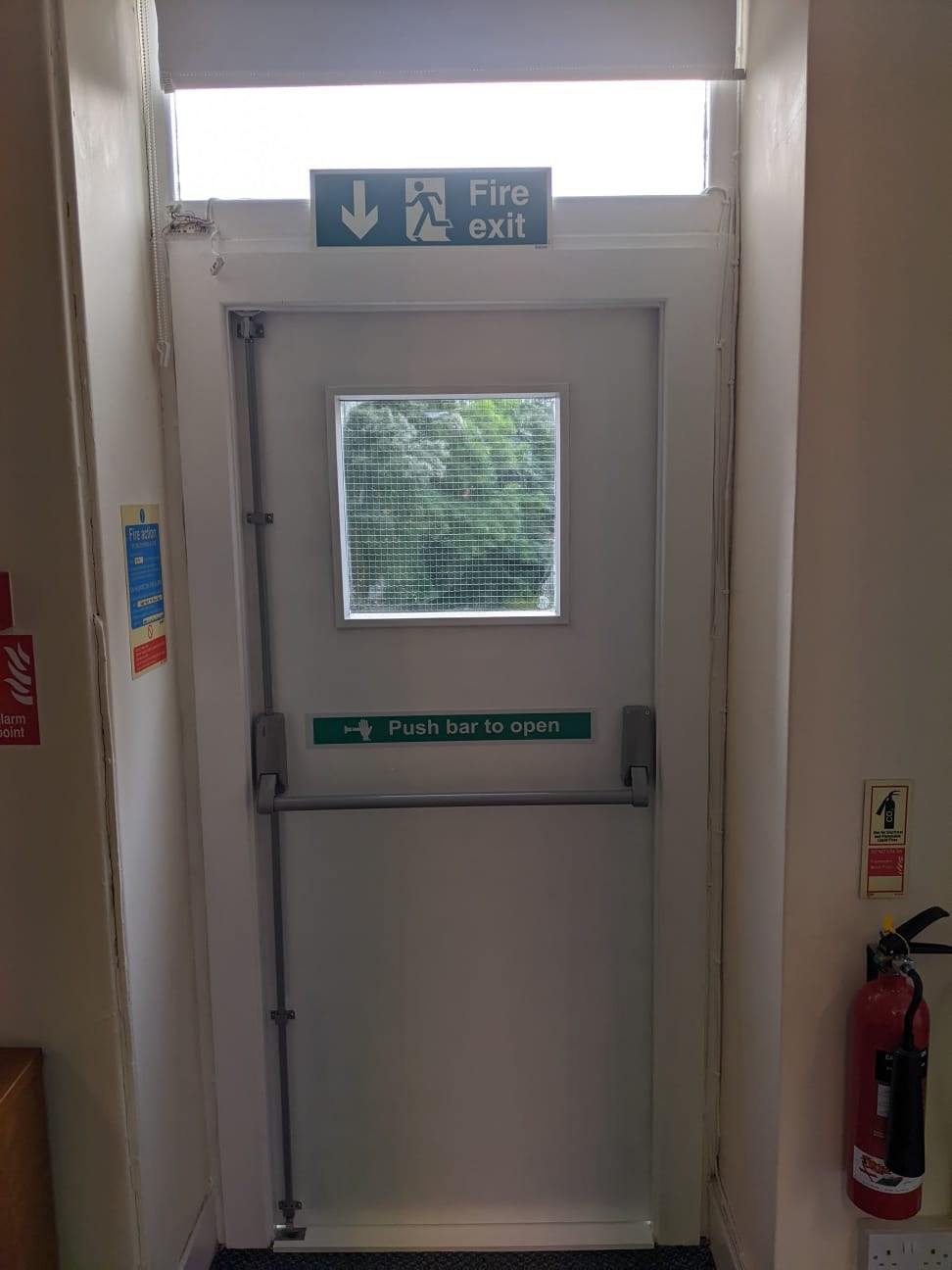 Interior view of the new fire exit door showing the panic push bar, push bar to open signage and fire exit sign above the doorway