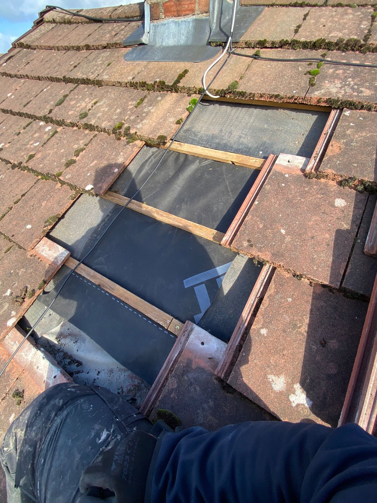 Section of roof tiles stripped back with new roofing membrane and treated battens installed before the tiles are re-laid