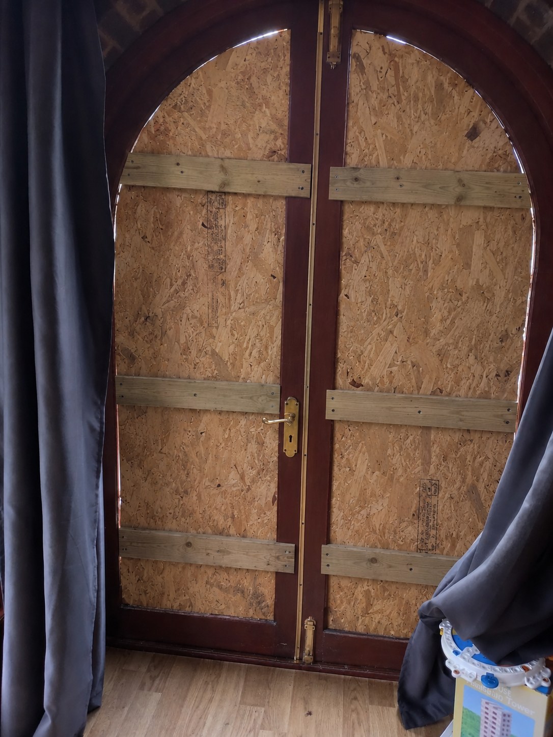 Arched hardwood double doors boarded from the inside with OSB sheets cut to the arch and fixed with timber battens