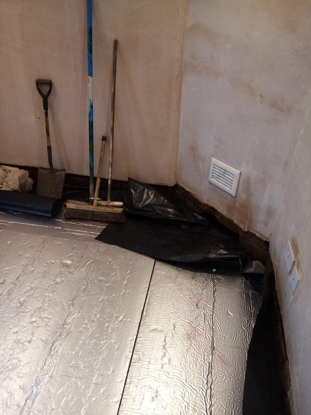 New concrete floor slab through an internal doorway with pipework protected at the base of the wall