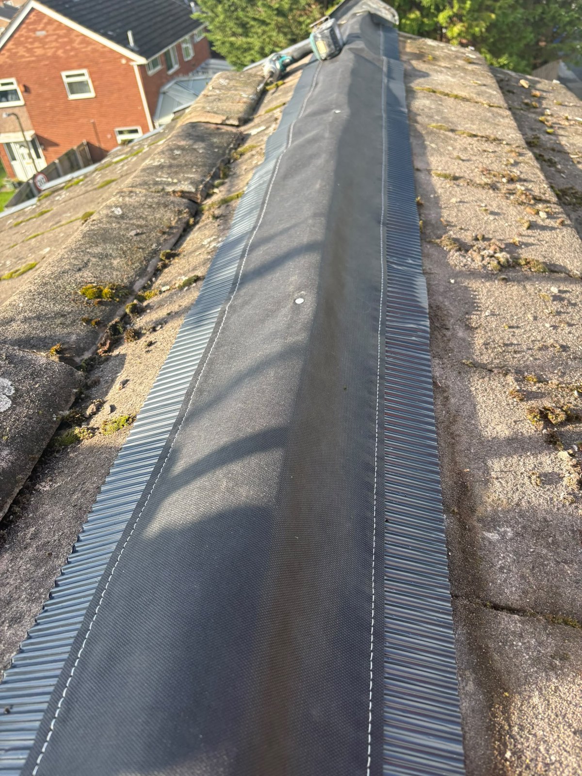 Ridge roll run out along the apex of a tiled roof over a new ridge batten, with fixings being installed