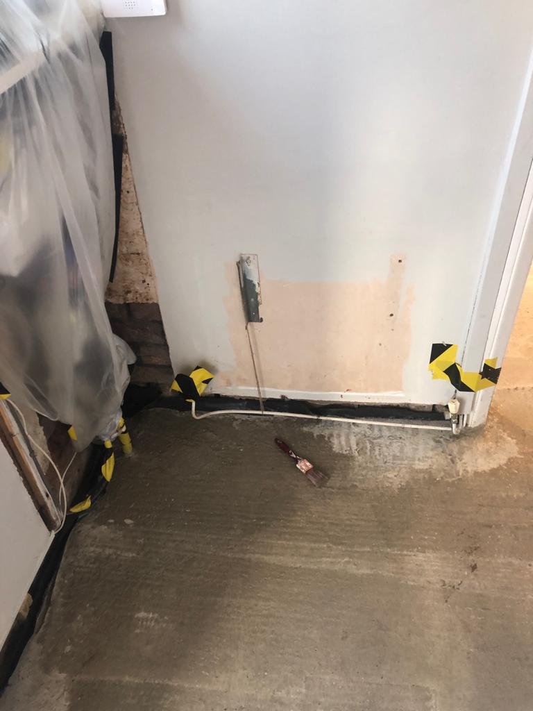 Newly poured concrete floor slab beneath a front window in a Wirral house with the damp-proof membrane visible at the edges