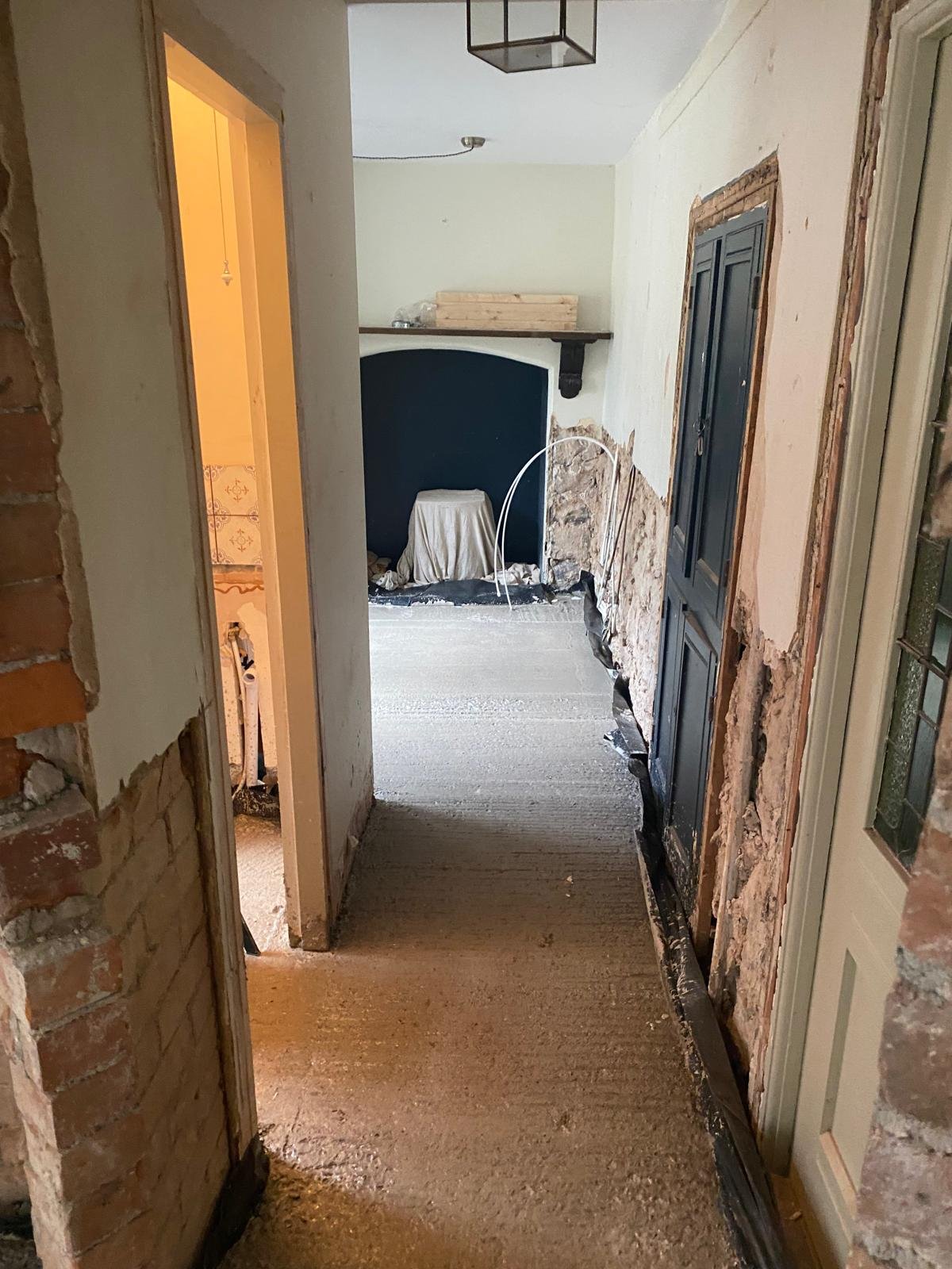 New concrete floor through the hallway of a period house with the damp-proof membrane dressed up the base of the walls