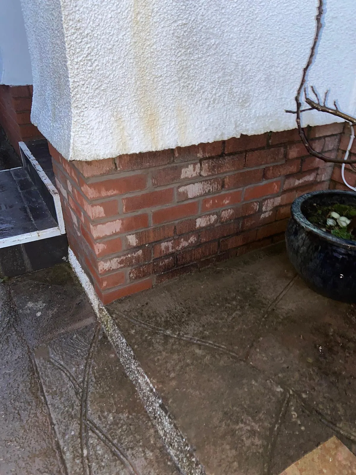 White salt deposits on the brickwork at the base of a rendered pier, with staining running down the render above