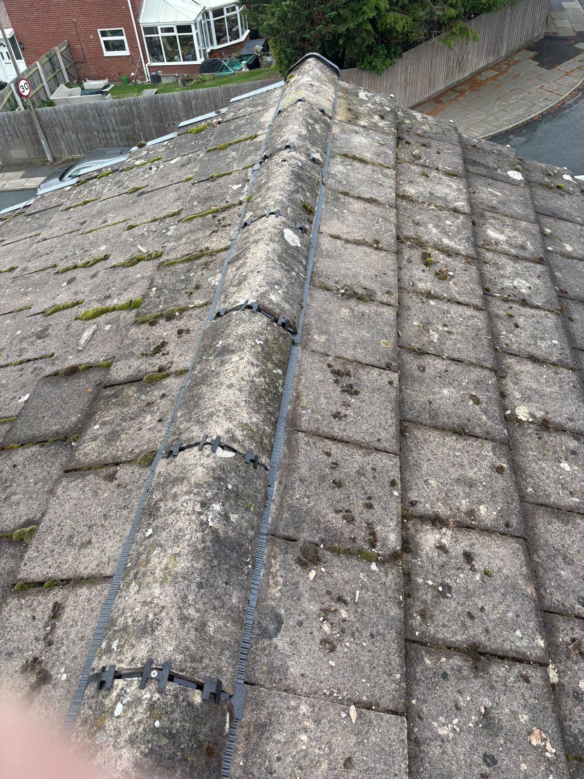 Completed dry ridge running the full length of a tiled roof with the ridge tiles mechanically fixed