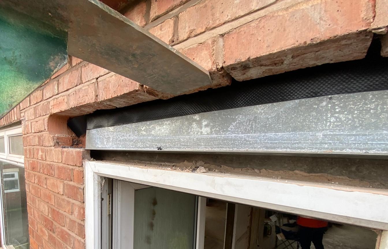New galvanised steel lintel installed over an opening with a damp-proof cavity tray laid over it, supported on temporary props
