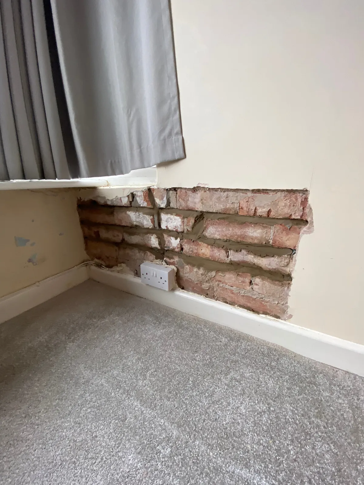Helical bars bedded into the mortar joints of an internal brick wall below a window, with the plaster taken off