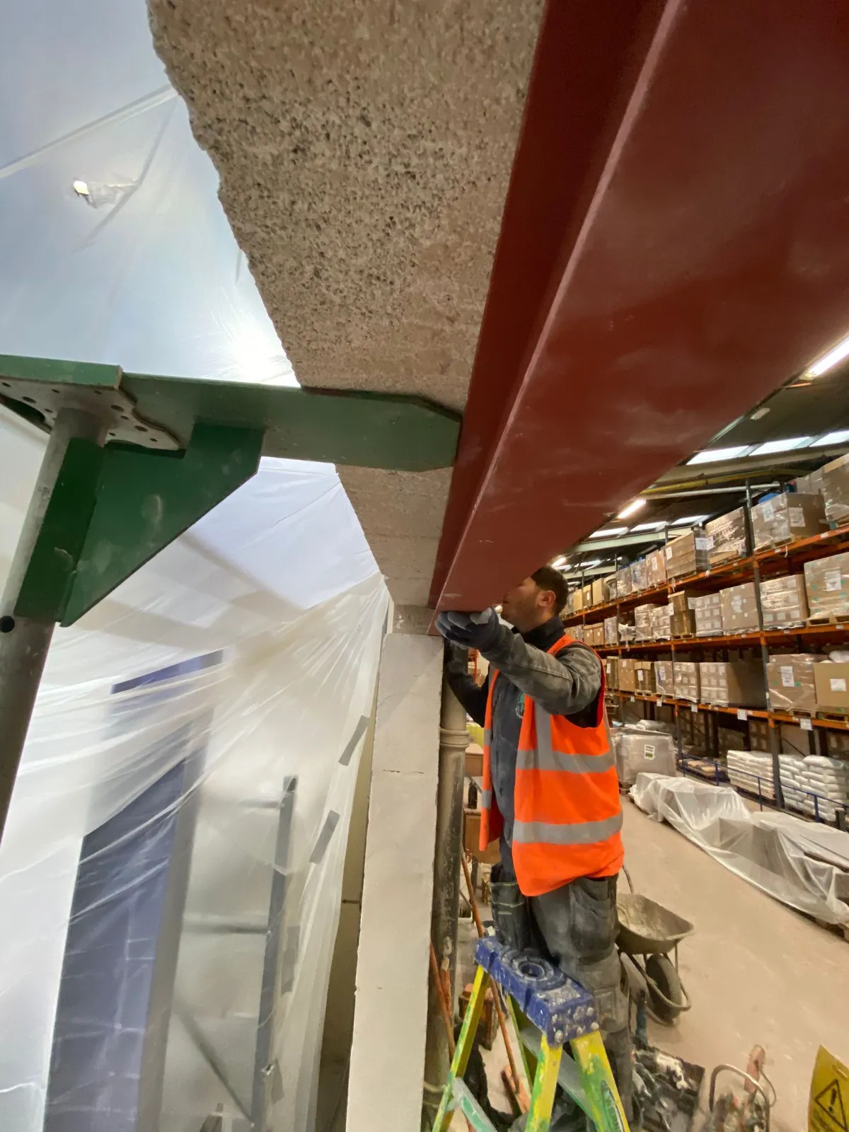 A new steel beam installed beneath a concrete slab in a commercial unit, supported on props while the work is completed