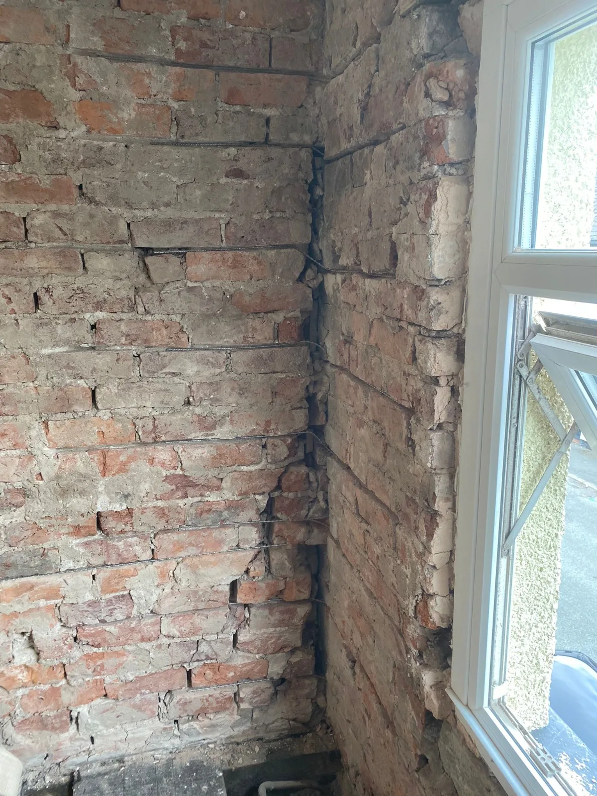 Exposed internal brickwork around the window during structural crack stitching and masonry reinforcement works.