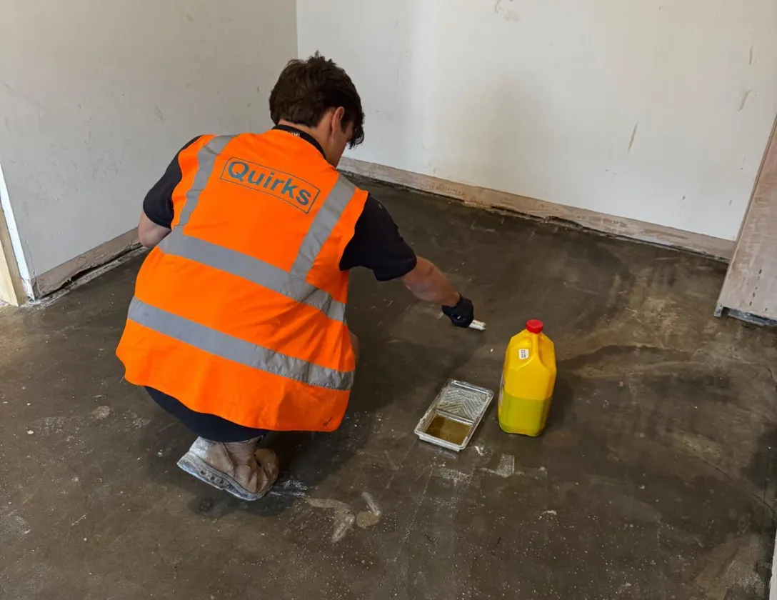 A Quirks operative applying a liquid damp-proof membrane to a prepared concrete floor slab