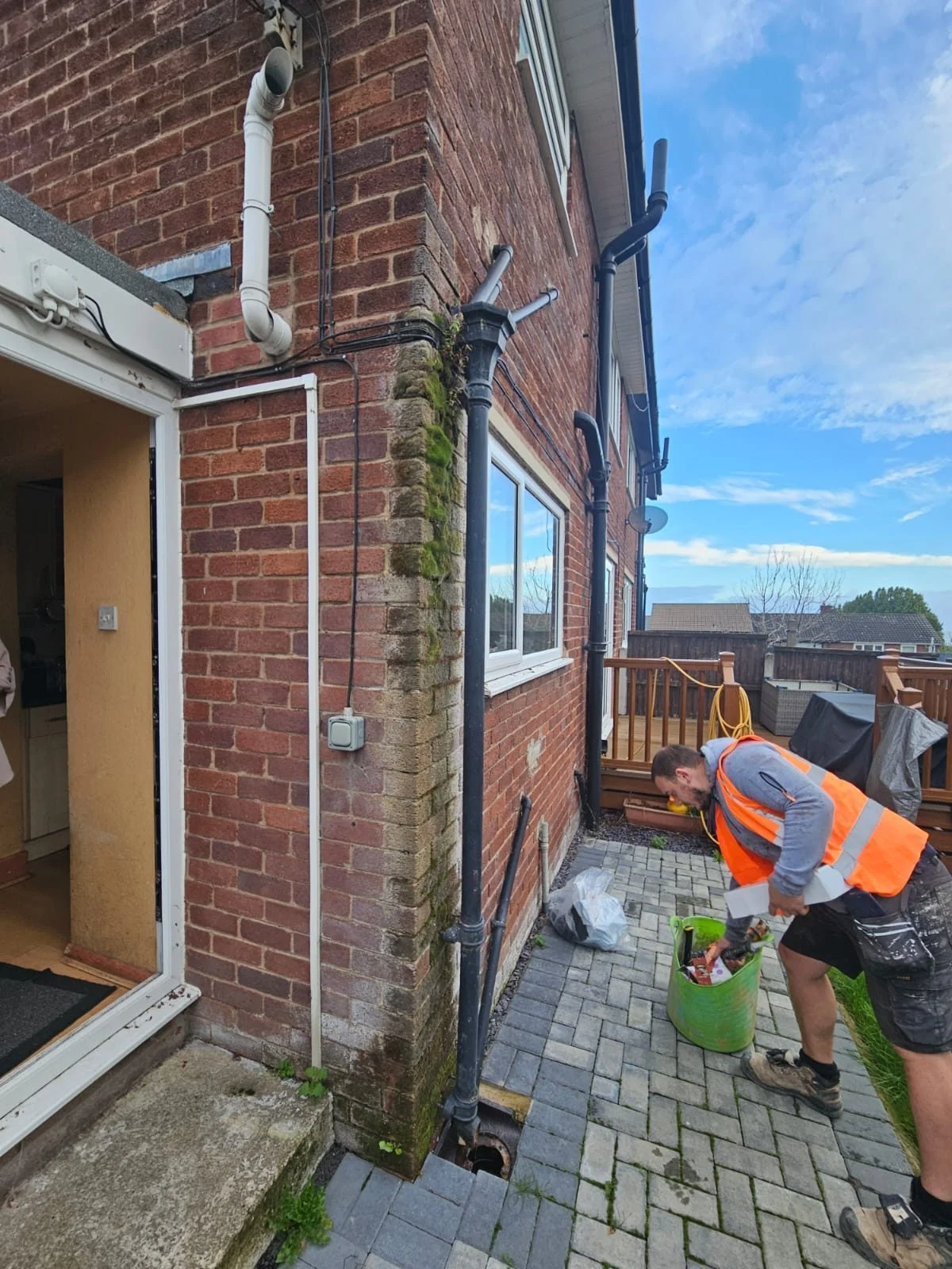Old cast-iron hopper head and downpipe pulled away from the wall of a house in Flintshire