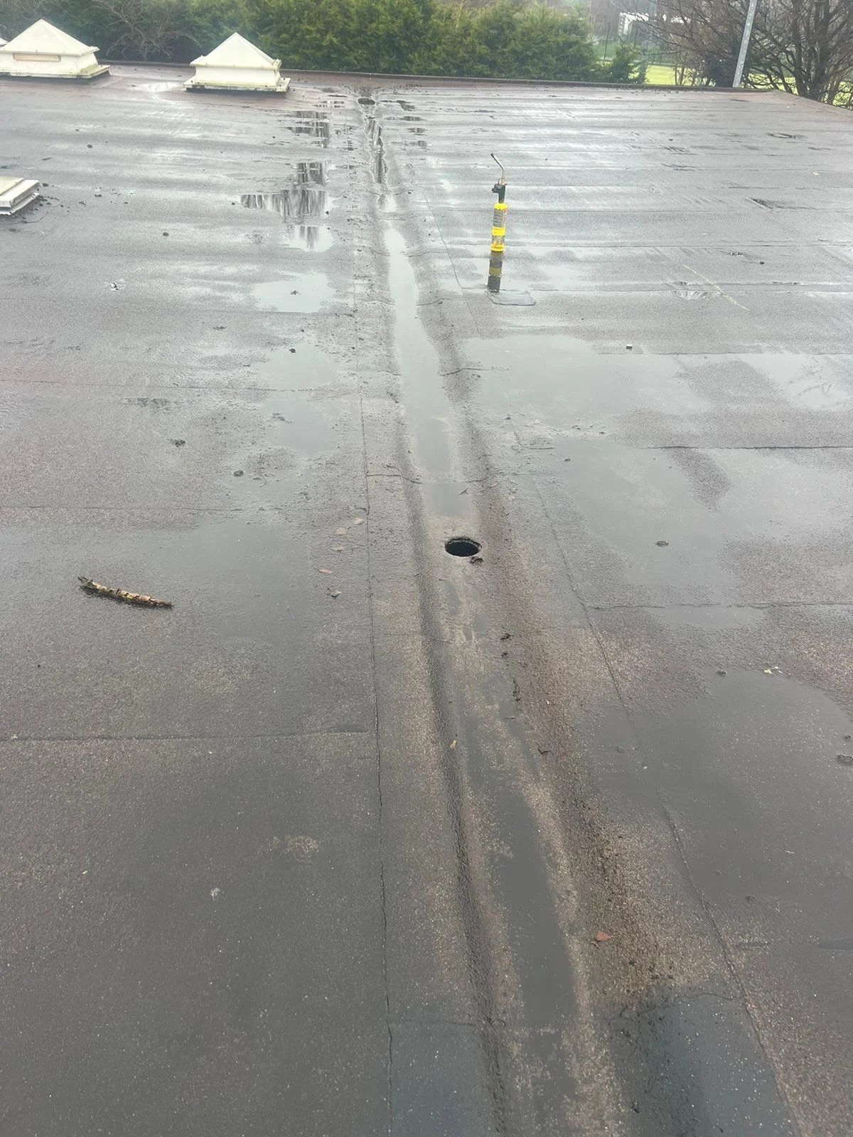 Flat roof covering in the rain, with water lying along a seam