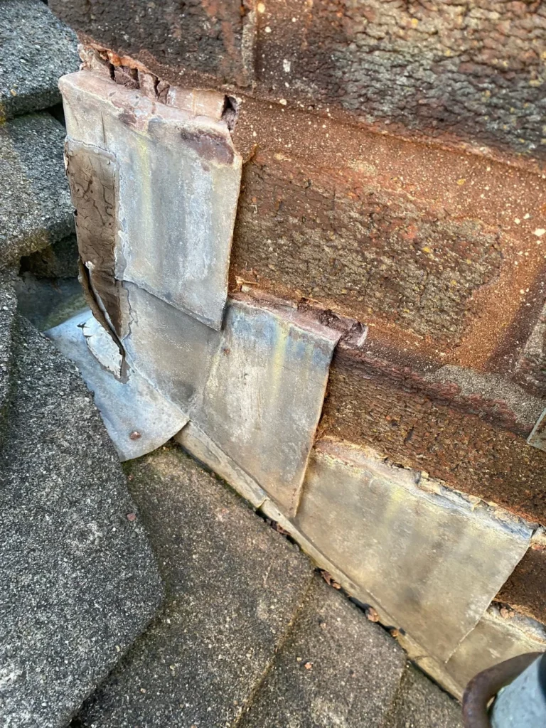 Lead flashing lifted away from the brickwork at a roof abutment