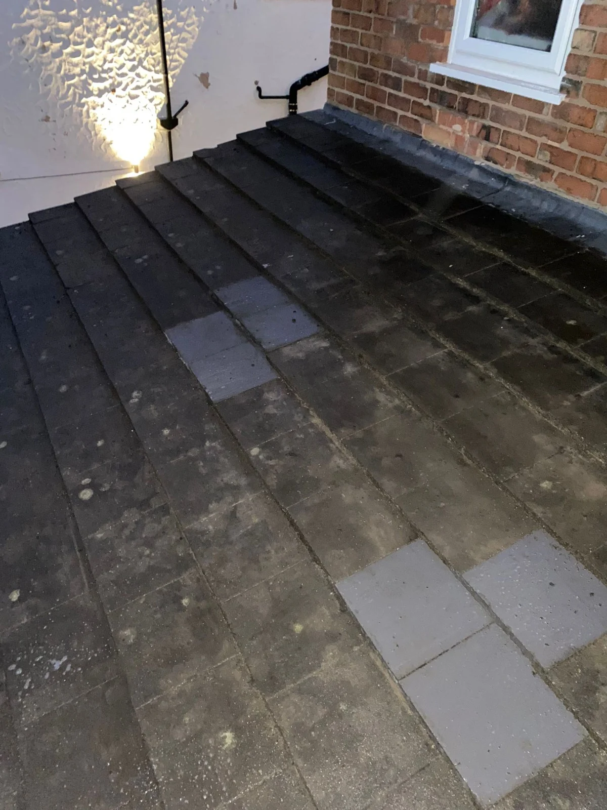 Slate roof at night with several lighter replacement slates among the old ones