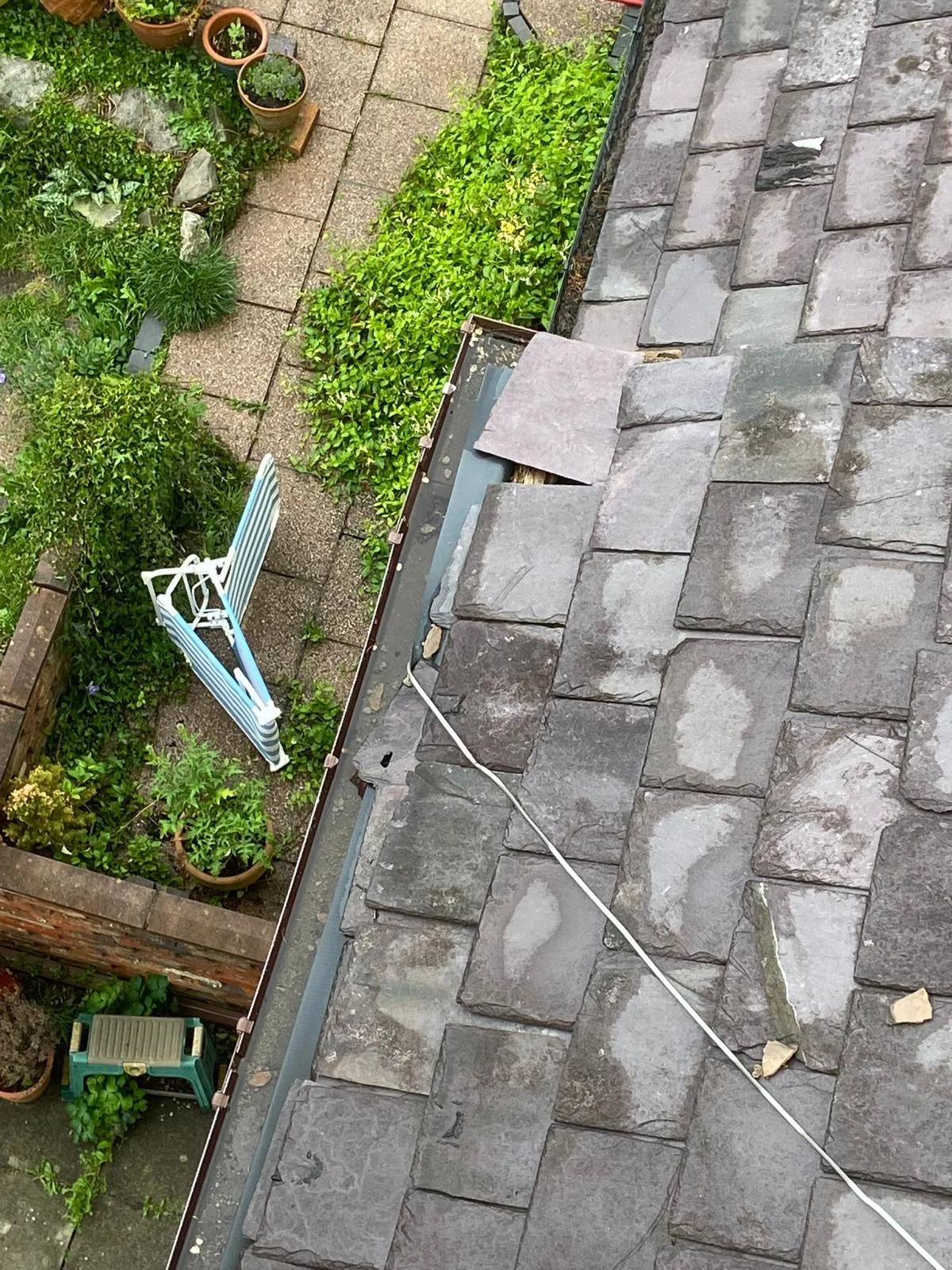 Slate roof with a slipped slate, seen from above with the garden below