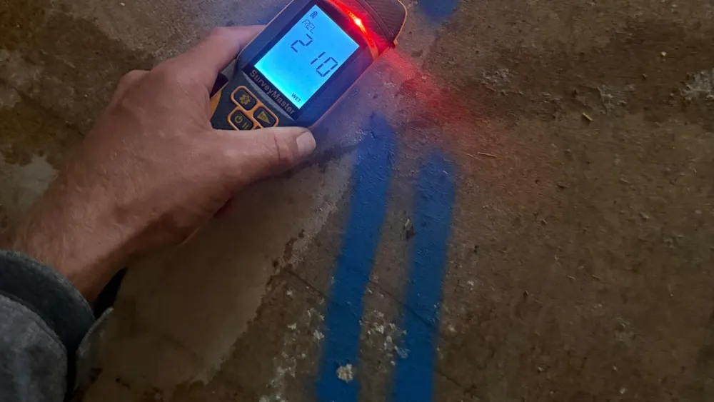A FOD Certified Surveyor taking a moisture reading on a concrete floor slab during a damp survey