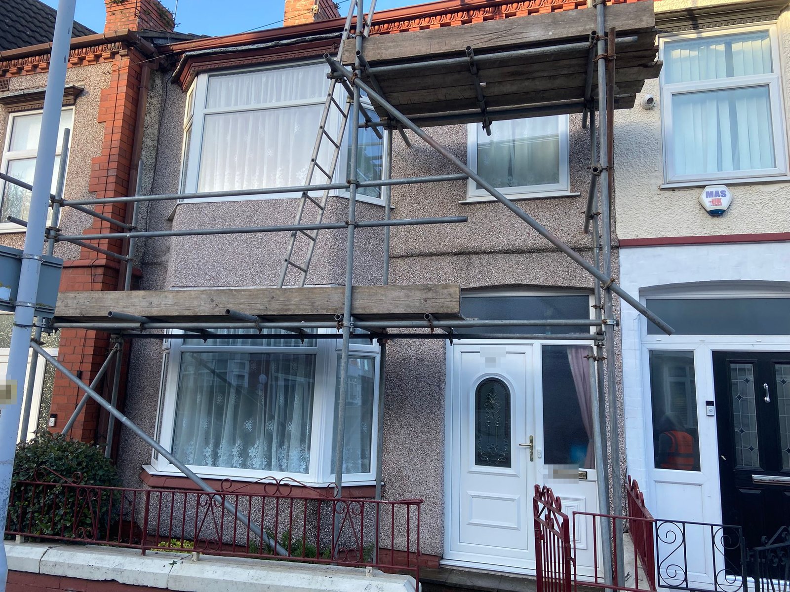 Rendered terraced house with a two-storey bay, re-rendered to match the front elevation, with the scaffold still up