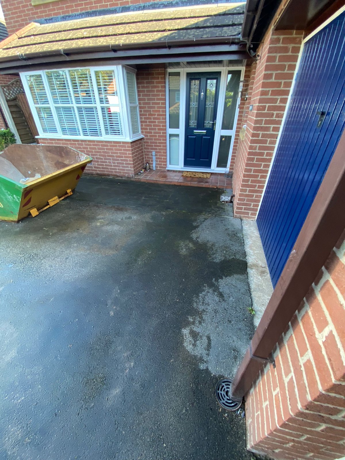 Front of a brick house with the original up-and-over garage door in place at the start of a partial garage conversion