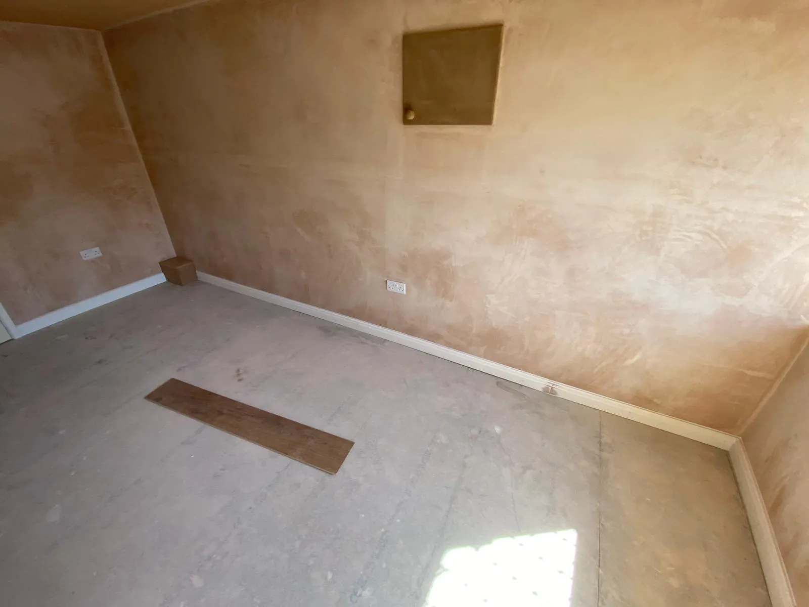 Consumer unit boxed into the plastered wall of a converted garage, with access maintained