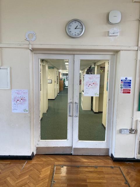 Pair of white double doors with large glazed panels in a wall between a school hall and a corridor