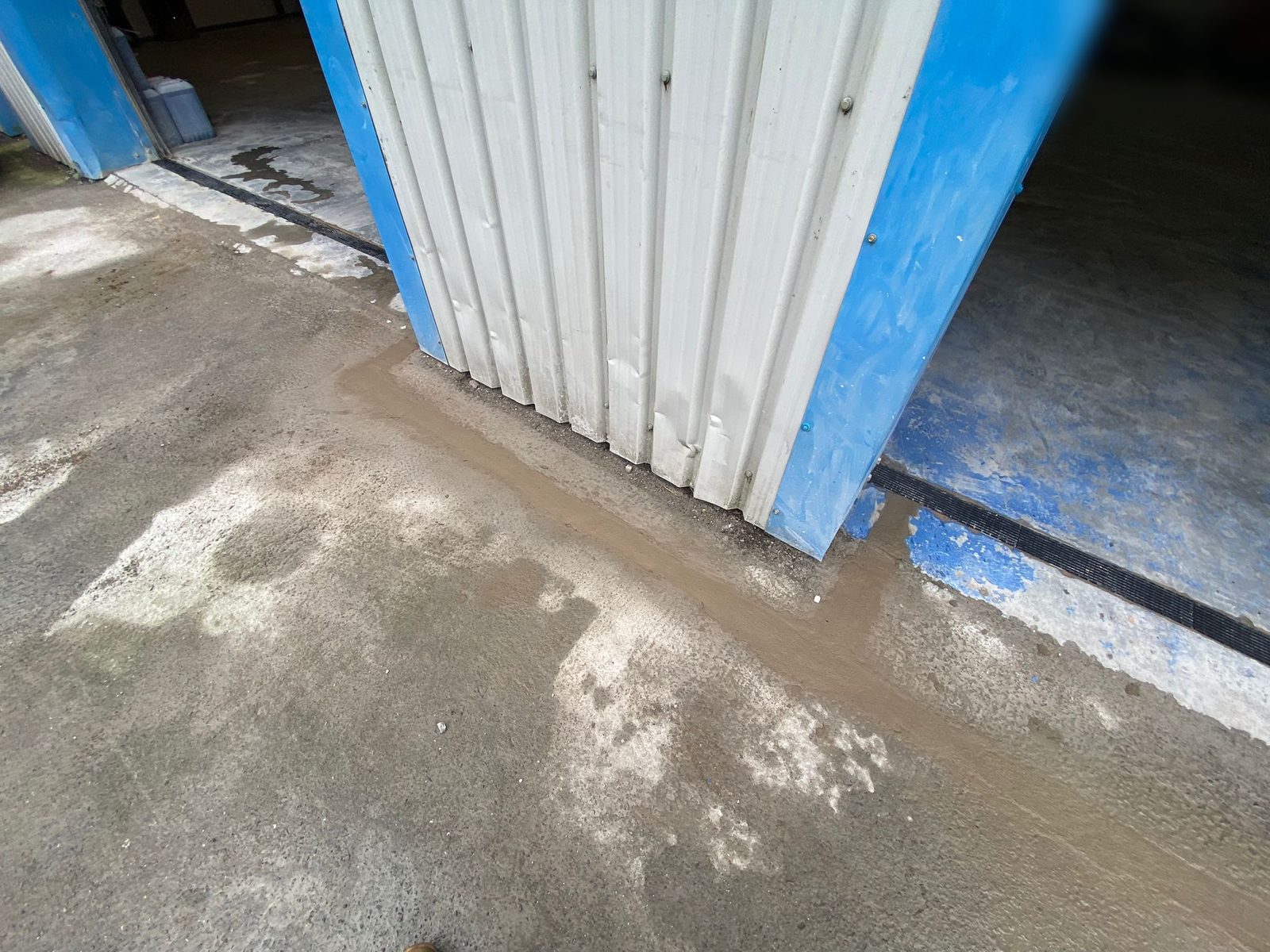 Freshly concreted trench along the base of a commercial unit where a new channel drain has been connected into the yard drainage