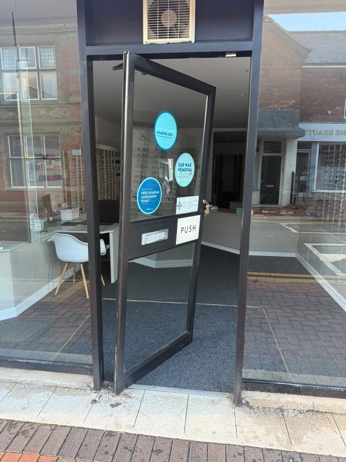 Commercial shop entrance door standing open and out of square after its bottom hinge failed
