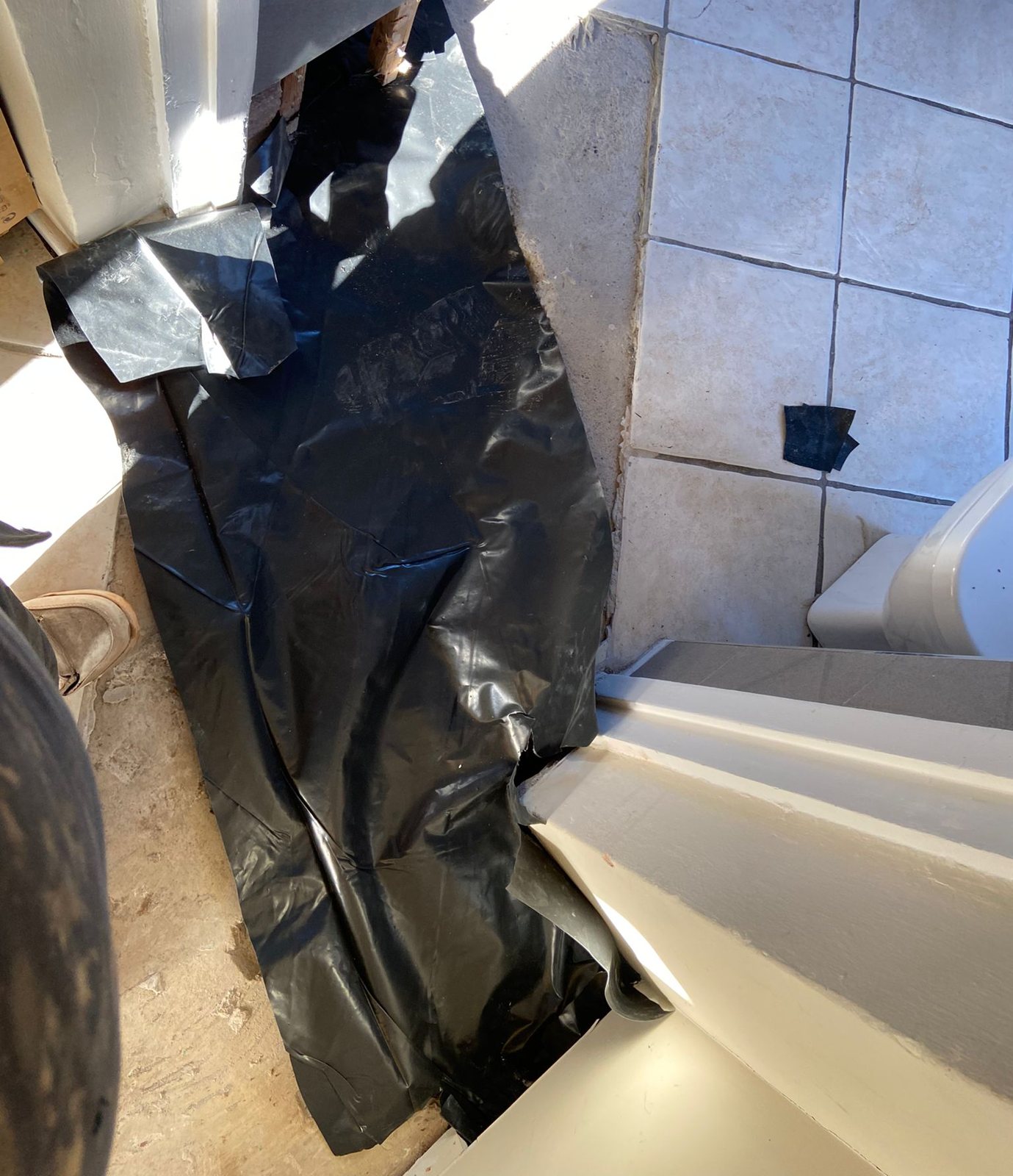 Black damp-proof membrane laid in an opening in a tiled floor