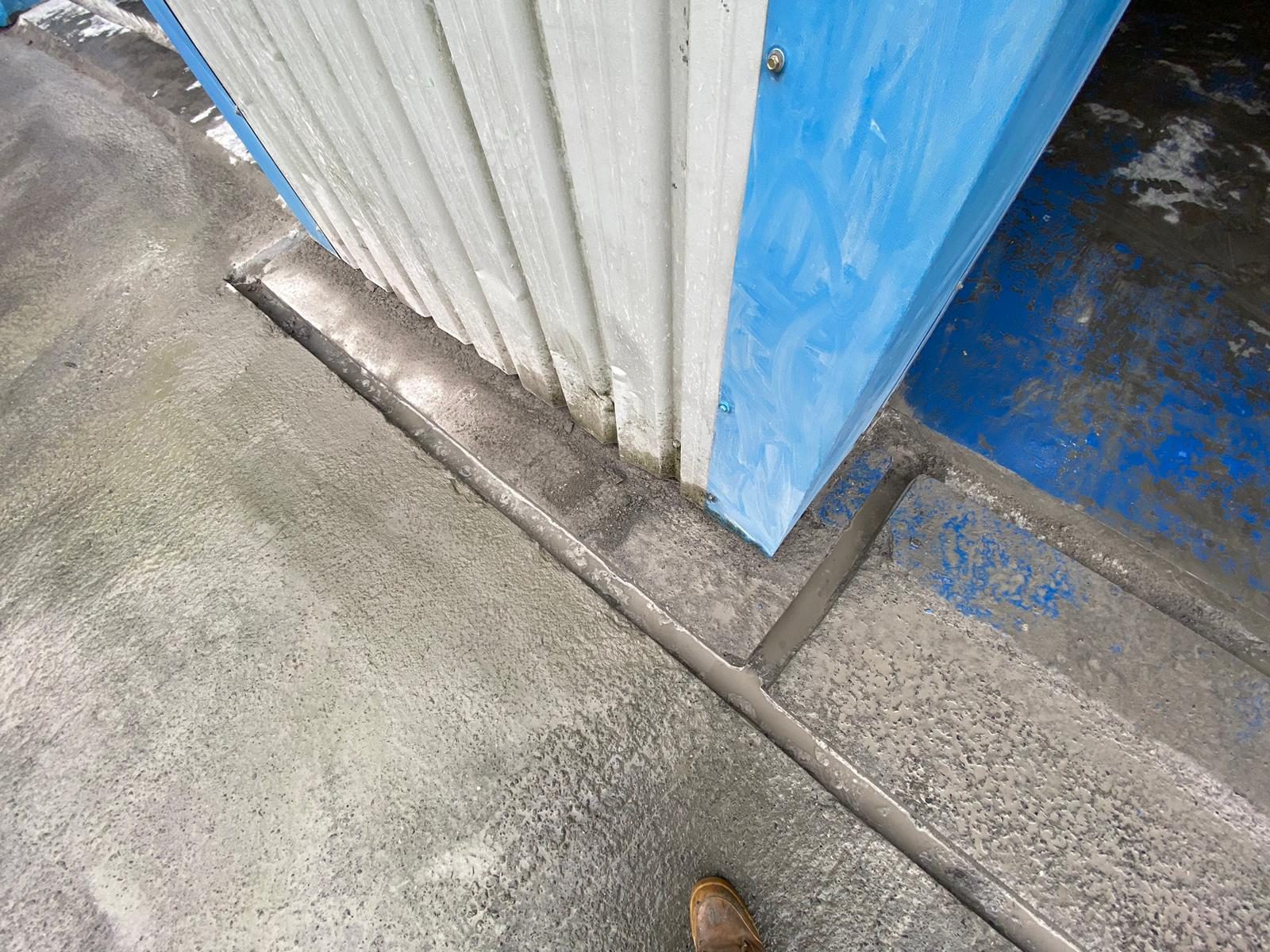Finished channel drain and mortar haunching along the threshold of a commercial unit directing surface water to the drain