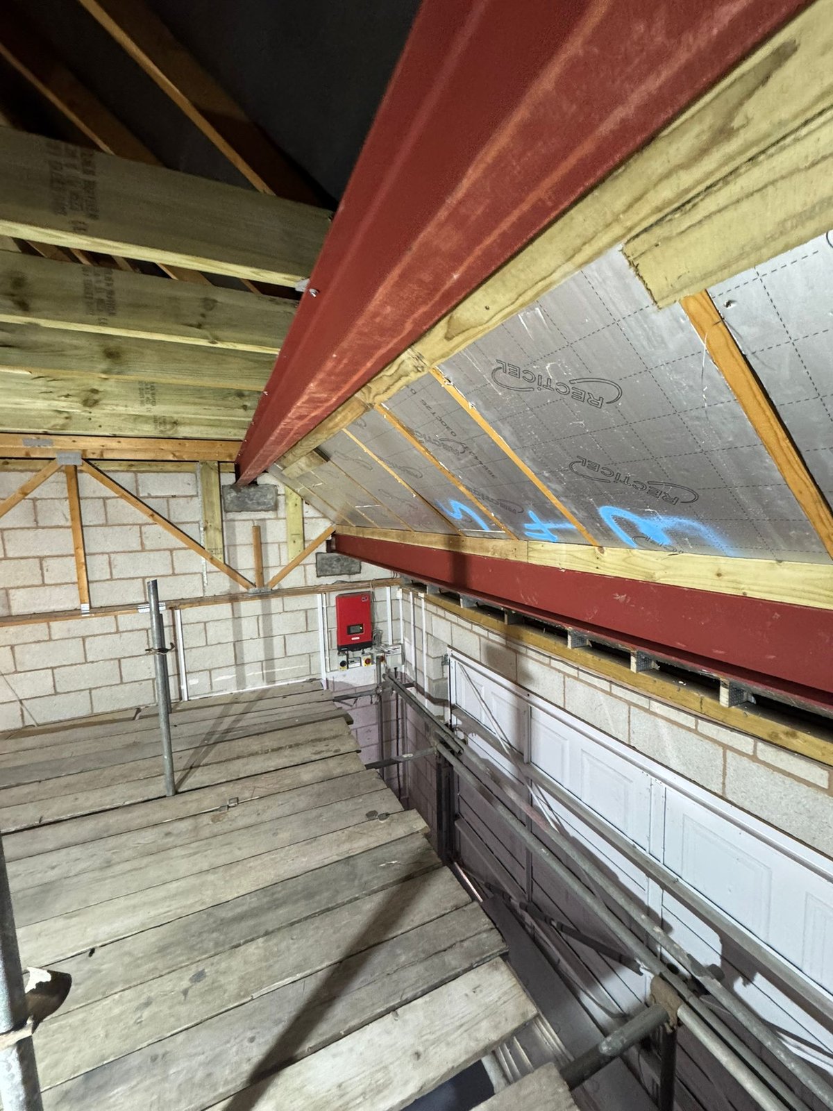 Steel beams installed within an altered roof structure alongside new timber supports and rigid insulation boards fitted between the rafters